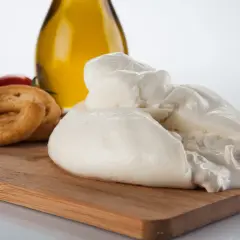 La burrata, un tesoro cremoso, si presenta su un tagliere con pomodorini, taralli e olio d'oliva.