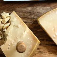 Due pezzi di formaggio stagionato, uno con scaglie e un piccolo tappo di legno, mostrano la differenza tra Gran Biraghi e Grana Padano.