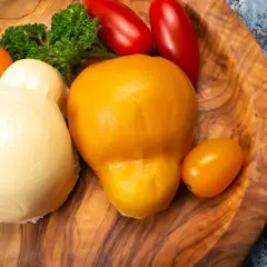 Due forme di formaggio, una bianca e una gialla, che sembrano provola e scamorza, sono la stessa cosa. Accanto, pomodorini e prezzemolo.