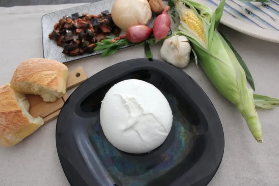 Mozzarella di bufala salernitana su piatto nero, con pane, verdure e mais.